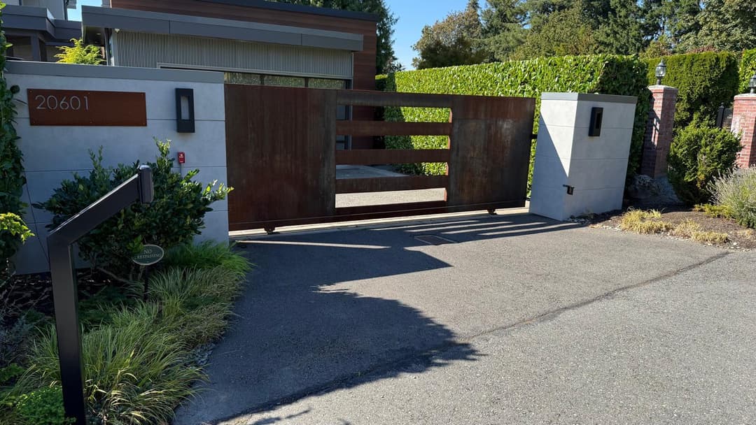 Modern patio gate at a luxury home with landscaped surroundings and a clear driveway.