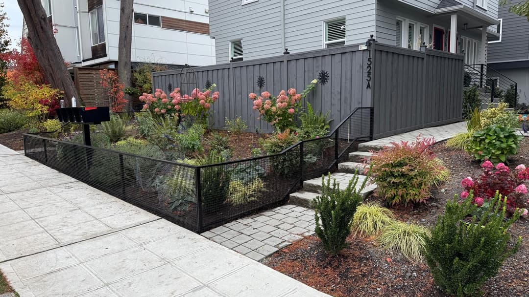 Front yard garden with colorful flowers, decorative fence, and modern house entrance.