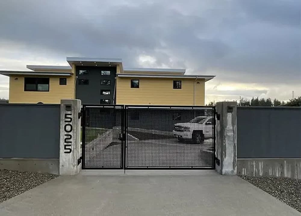 Modern home entrance with a gated driveway and stylish architecture in a suburban setting.